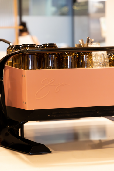 Rose gold espresso machine with 'La Marzocco' branding on a blurred background