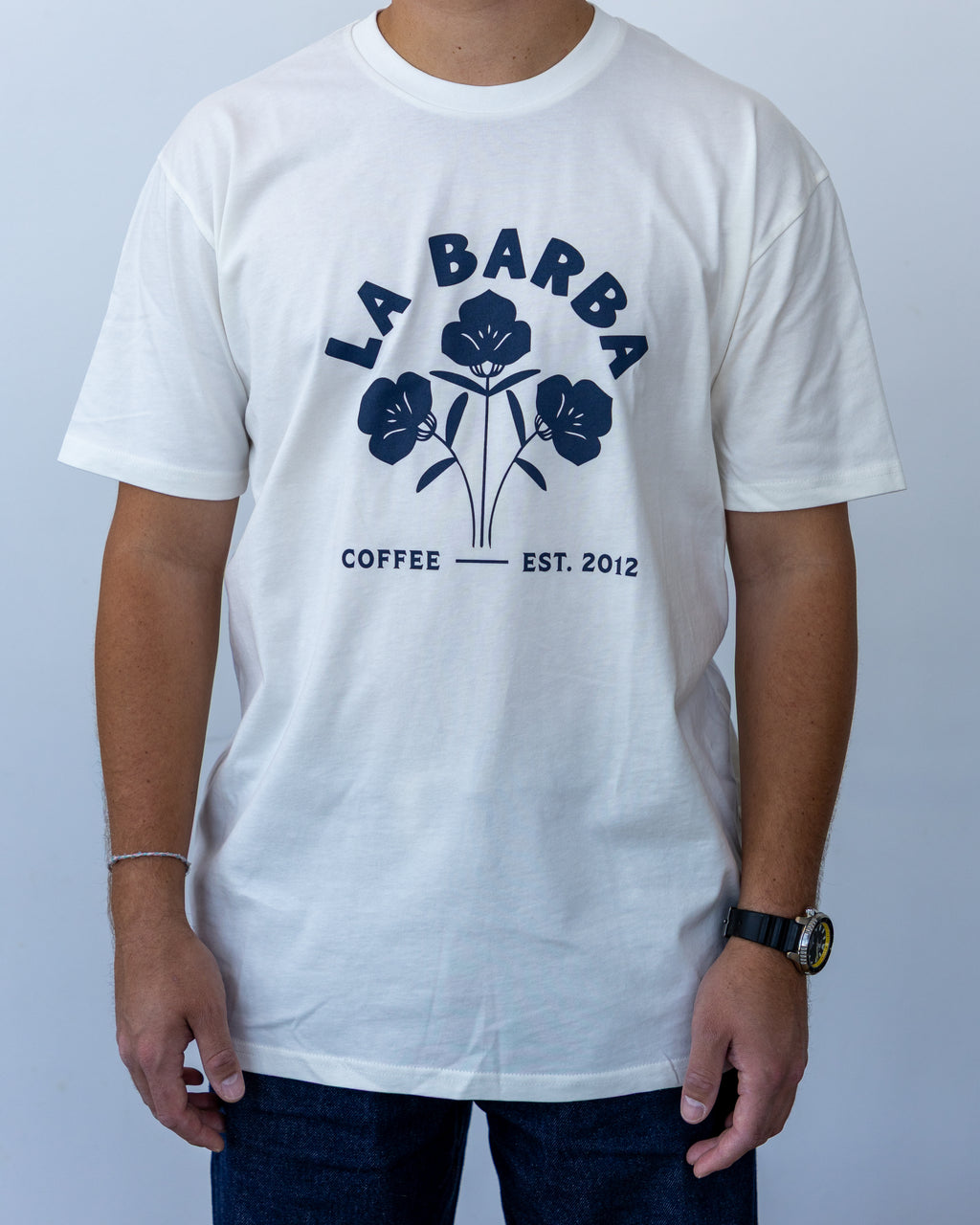 Person wearing a white t-shirt with 'La Barba Coffee' logo on a plain background