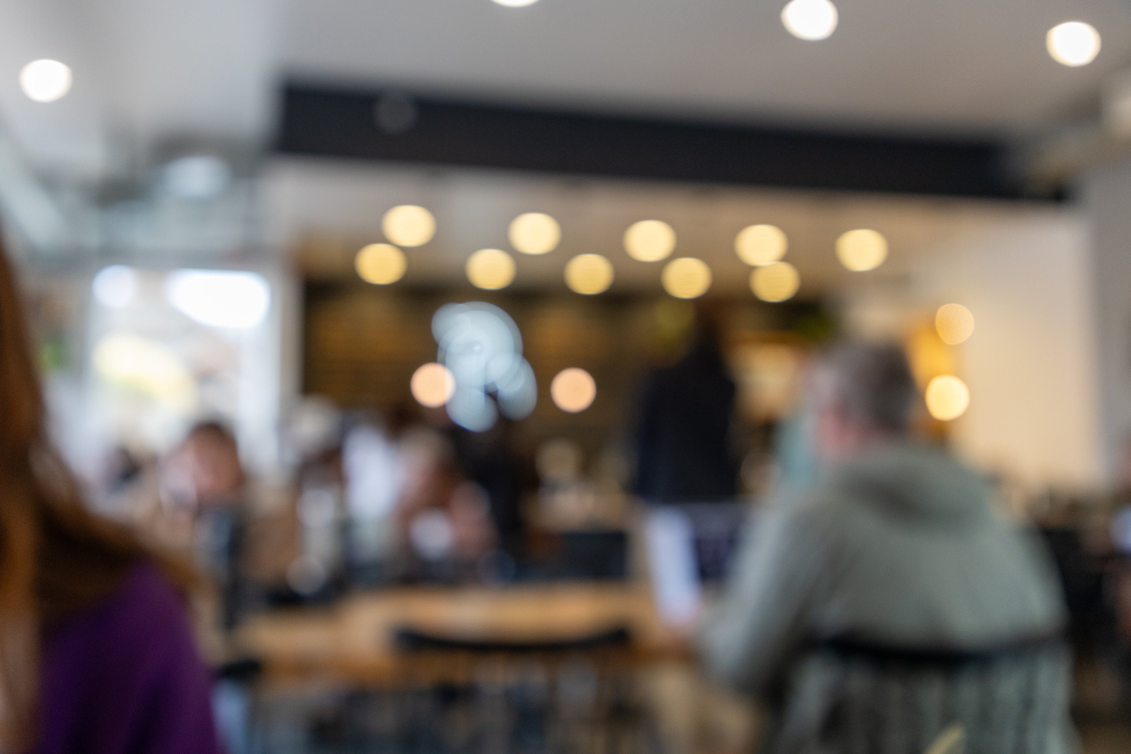 Blurred image of a restaurant interior with people sitting at tables.