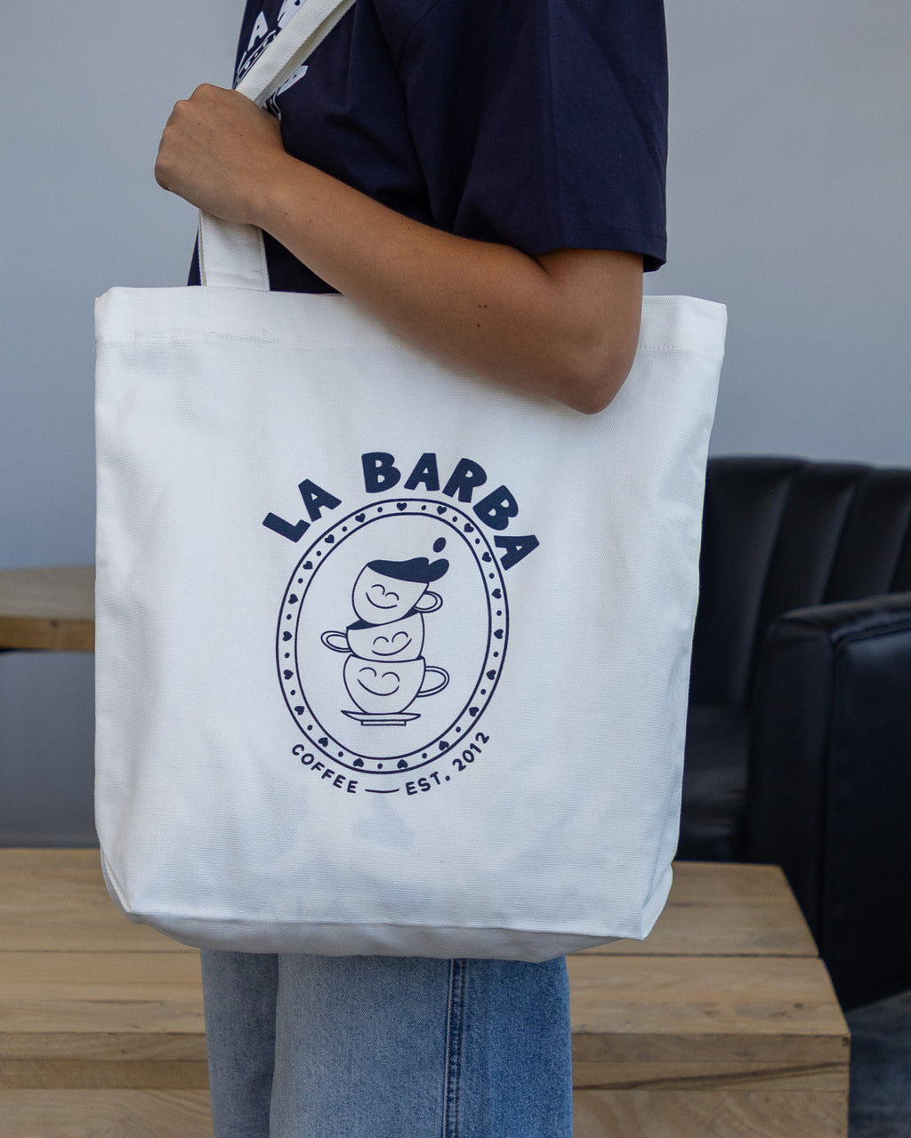 Person holding a white tote bag with 'La Barba' logo