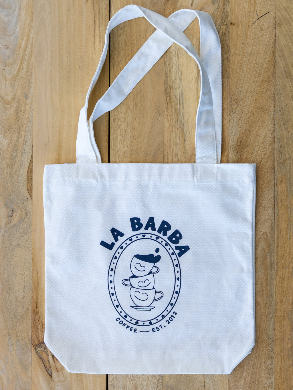 White tote bag with 'La Barba Coffee' logo on a wooden surface