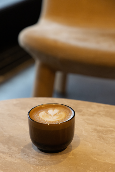 Cappuccino with latte art on a wooden table with a blurred chair in the background