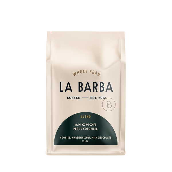 The image features a 12oz bag of La Barba Coffee, specifically their Anchor Blend. The bag is designed with an ivory white background, prominently displaying the brand name "La Barba" in large, elegant letters. It highlights the coffee blend's origins, Peru and Colombia, and includes a description of the flavor profile, including notes of Cookies, Marshmallow, amd Milk Chocolate. The design exudes a premium and modern feel with a minimalist, sophisticated look.
