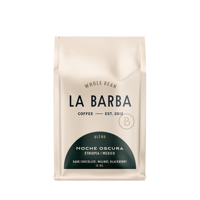 The image features a 12oz bag of La Barba Coffee, specifically their Noche Oscura Blend. The bag is designed with an ivory white background, prominently displaying the brand name 