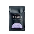 The image features a 12oz bag of La Barba Coffee, specifically their Colombia Decaf El Nevado. The bag is designed with a dark background, prominently displaying the brand name "La Barba" in large, elegant letters. It highlights the coffee's origin, Colombia, along with a description of the flavor profile, including notes of orange zest, chocolate, and nougat. The design exudes a premium and modern feel with a minimalist, sophisticated look.