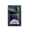 The image features a 12oz bag of La Barba Coffee, specifically their Ecuador Hacienda La Papaya. The bag is designed with a dark background, prominently displaying the brand name "La Barba" in large, elegant letters. It highlights the coffee's origin, Ecuador, along with a description of the flavor profile, including notes of blackberry, candy sugar, and rose. The design exudes a premium and modern feel with a minimalist, sophisticated look.