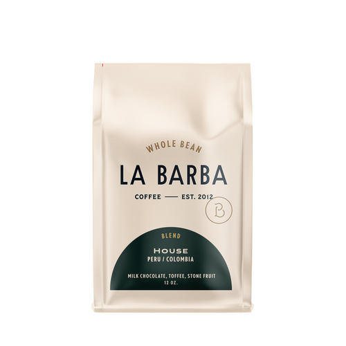 The image features a 12oz bag of La Barba Coffee, specifically their House Blend. The bag is designed with an ivory white background, prominently displaying the brand name "La Barba" in large, elegant letters. It highlights the coffee blend's origins, Peru and Colombia, and includes a description of the flavor profile, including notes of Milk Chocolate, Toffee, and Stone Fruit. The design exudes a premium and modern feel with a minimalist, sophisticated look.