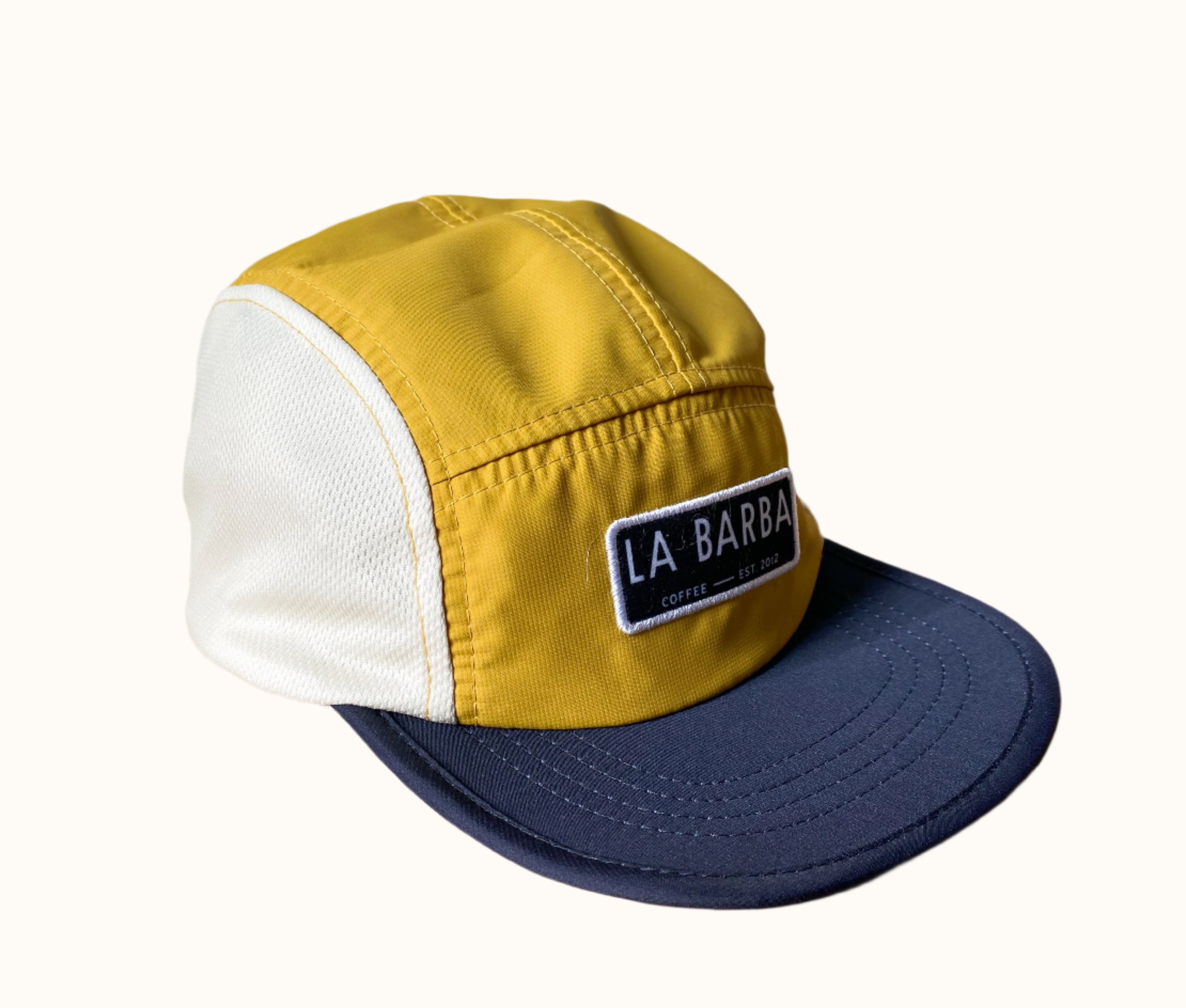 A La Barba branded cap with yellow and white colors and mesh side panels.