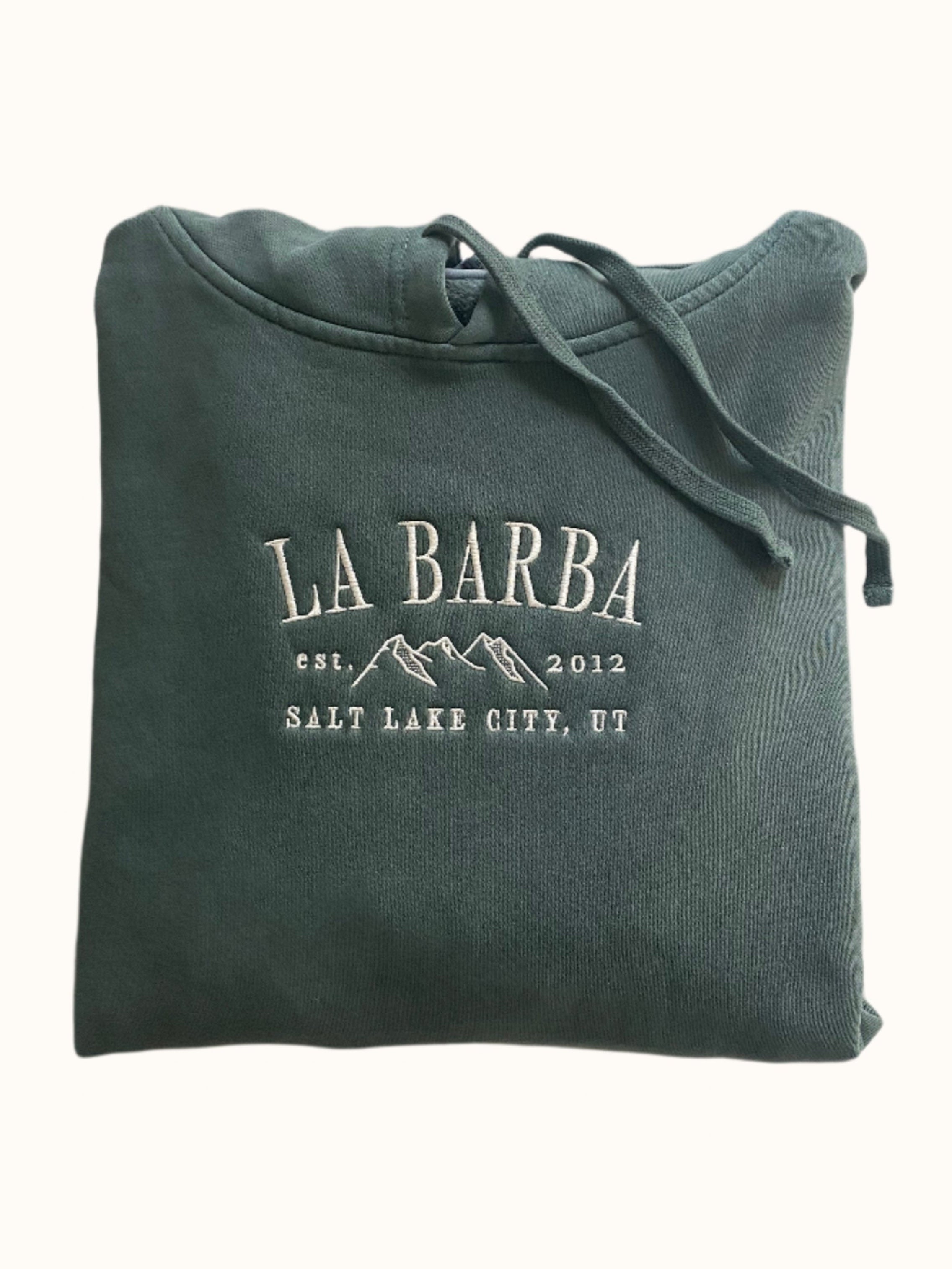 A green hooded sweatshirt with 'La Barba' branding and the text 'Salt Lake City, UT' along with a mountain range illustration.
