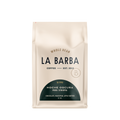 The image features a 12oz bag of La Barba Coffee, specifically their Noche Oscura Blend. The bag is designed with an ivory white background, prominently displaying the brand name "La Barba" in large, elegant letters. It highlights the coffee blend's origins, Peru and Ethiopia, and includes a description of the flavor profile, including notes of Chocolate, Marzipan, and Apple Butter. The design exudes a premium and modern feel with a minimalist, sophisticated look.