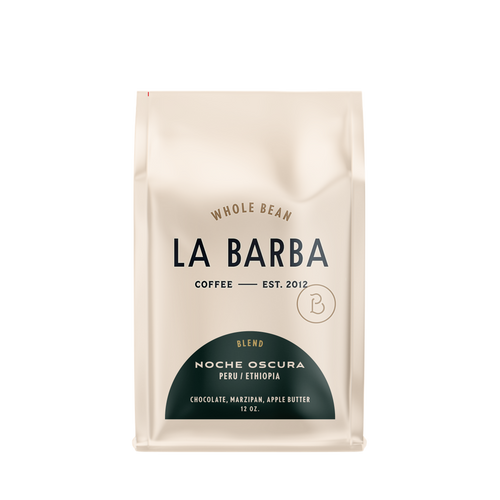 The image features a 12oz bag of La Barba Coffee, specifically their Noche Oscura Blend. The bag is designed with an ivory white background, prominently displaying the brand name "La Barba" in large, elegant letters. It highlights the coffee blend's origins, Peru and Ethiopia, and includes a description of the flavor profile, including notes of Chocolate, Marzipan, and Apple Butter. The design exudes a premium and modern feel with a minimalist, sophisticated look.