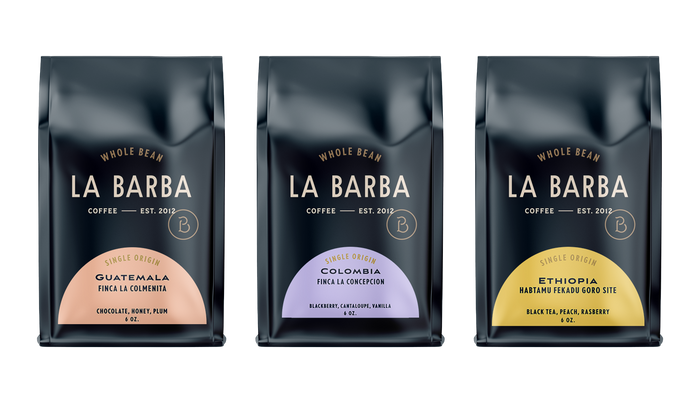 Three La Barba Coffee single-origin whole-bean bags arranged side by side, featuring Guatemala Finca La Colmenita with notes of chocolate, honey, and plum; Colombia Finca La Concepcion with notes of blackberry, cantaloupe, and vanilla; and Ethiopia Habtamu Fekadu Goro Site with notes of black tea, peach, and raspberry. Premium specialty coffee packaging with a modern dark design and colorful half-moon origin labels