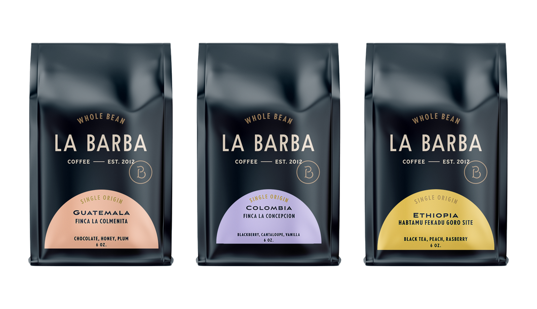 Three La Barba Coffee single-origin whole-bean bags arranged side by side, featuring Guatemala Finca La Colmenita with notes of chocolate, honey, and plum; Colombia Finca La Concepcion with notes of blackberry, cantaloupe, and vanilla; and Ethiopia Habtamu Fekadu Goro Site with notes of black tea, peach, and raspberry. Premium specialty coffee packaging with a modern dark design and colorful half-moon origin labels