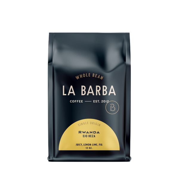 The image features a 12oz bag of La Barba Coffee, specifically their Rwanda Ejo Heza single-origin coffee. The bag is designed with a dark background, prominently displaying the brand name "La Barba" in large, elegant letters. It highlights the coffee's origin, Rwanda, along with a description of the flavor profile, including notes of juicy, lemon-lime, and fig. The design exudes a premium and modern feel with a minimalist, sophisticated look.
