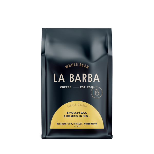 The image features a 12oz bag of La Barba Coffee, specifically their Rwanda Natural single-origin coffee. The bag is designed with a dark background, prominently displaying the brand name "La Barba" in large, elegant letters. It highlights the coffee's origin, Rwanda, along with a description of the flavor profile, including notes of Blueberry Jam, Hibiscus, and Watermelon. The design exudes a premium and modern feel with a minimalist, sophisticated look.