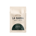 The image features a 12oz bag of La Barba Coffee, specifically their Anchor Blend. The bag is designed with an ivory white background, prominently displaying the brand name "La Barba" in large, elegant letters. It highlights the coffee blend's origins, Guatemala and Brazil, and includes a description of the flavor profile, including notes of Cookies, Marshmallow, and Milk Chocolate. The design exudes a premium and modern feel with a minimalist, sophisticated look.
