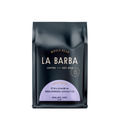 The image features a 12oz bag of La Barba Coffee, specifically their Colombia Diego Bermudez Castillo Y-05. The bag is designed with a dark background, prominently displaying the brand name "La Barba" in large, elegant letters. It highlights the coffee's origin, Colombia, along with a description of the flavor profile, including notes of peach, apple, and lychee. The design exudes a premium and modern feel with a minimalist, sophisticated look.